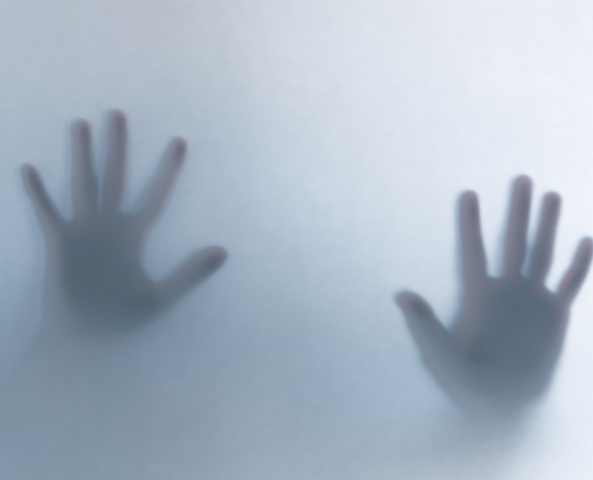 Defocused scary ghost hands behind a white glass background